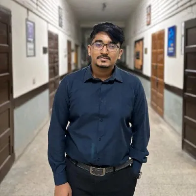 Saran Deb Nath, in glasses and a navy shirt, standing in a long corridor