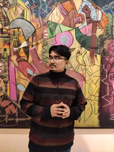 Saran Deb Nath in a striped sweater in front of a large colourful abstract painting